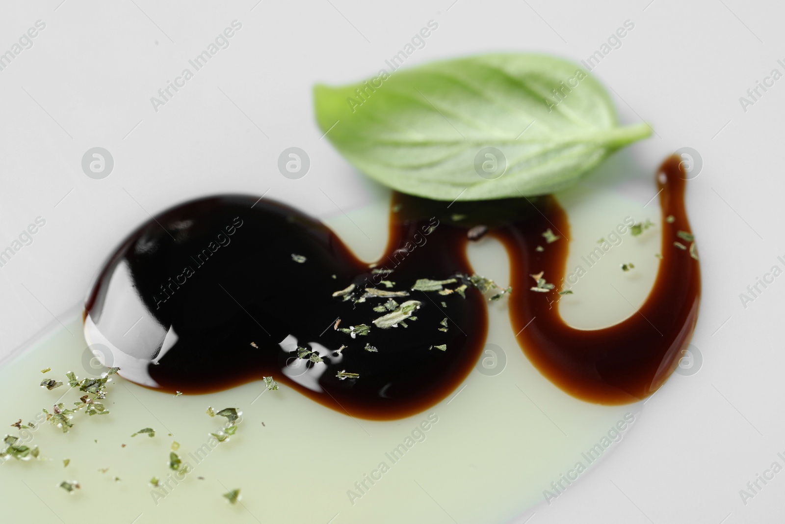 Photo of Delicious balsamic vinegar with olive oil, basil and herbs on white background, closeup