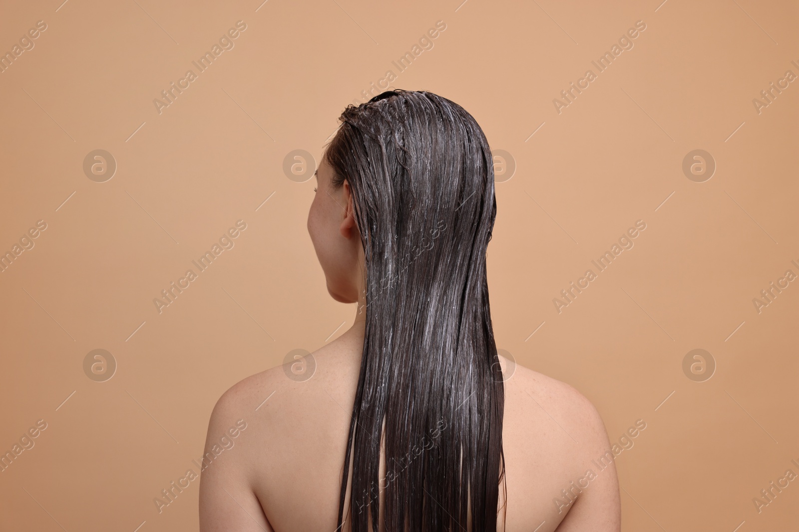 Photo of Woman with applied hair mask on beige background, back view