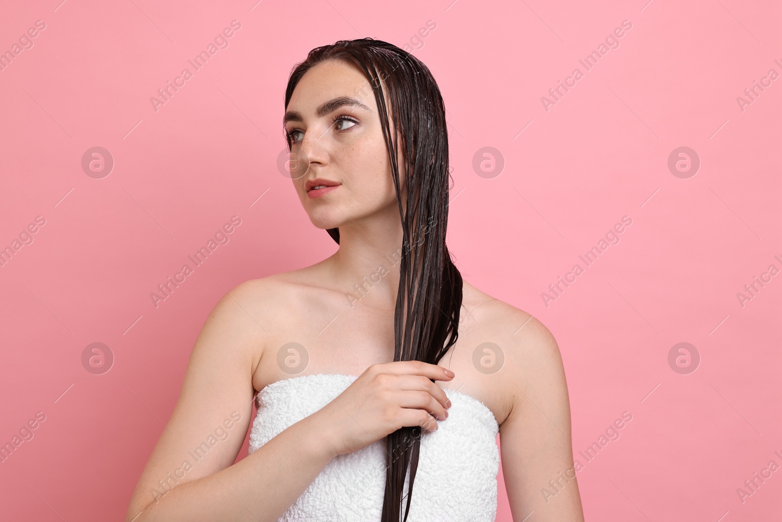 Photo of Beautiful woman applying hair mask on pink background