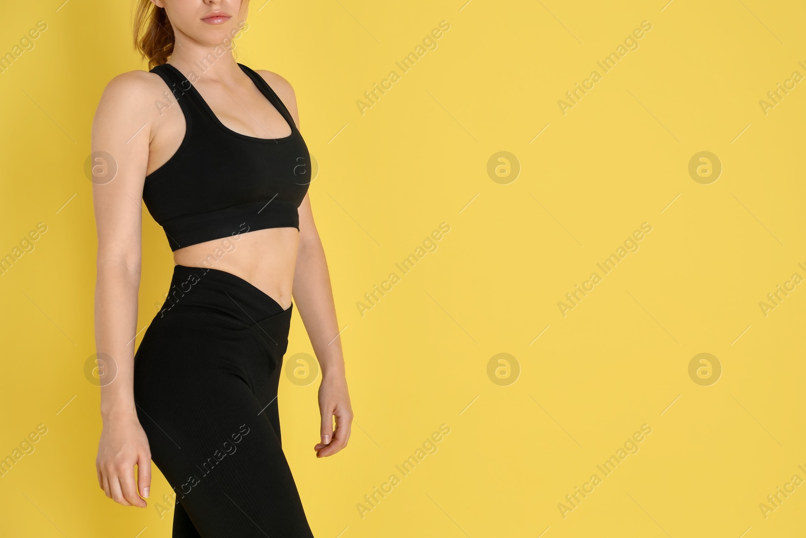 Photo of Woman with slim body posing on yellow background, closeup. Space for text