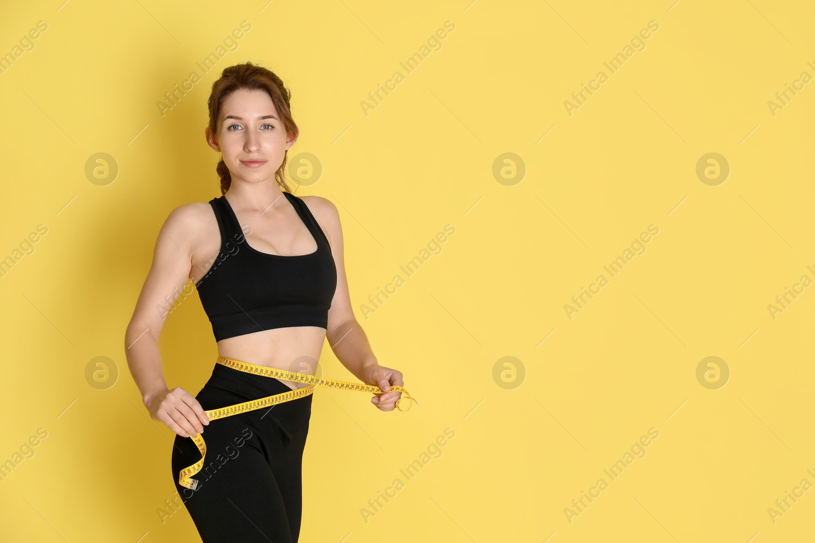 Photo of Woman with measuring tape showing her slim body against yellow background, space for text