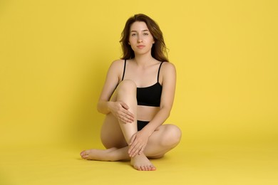 Woman with slim body posing on yellow background