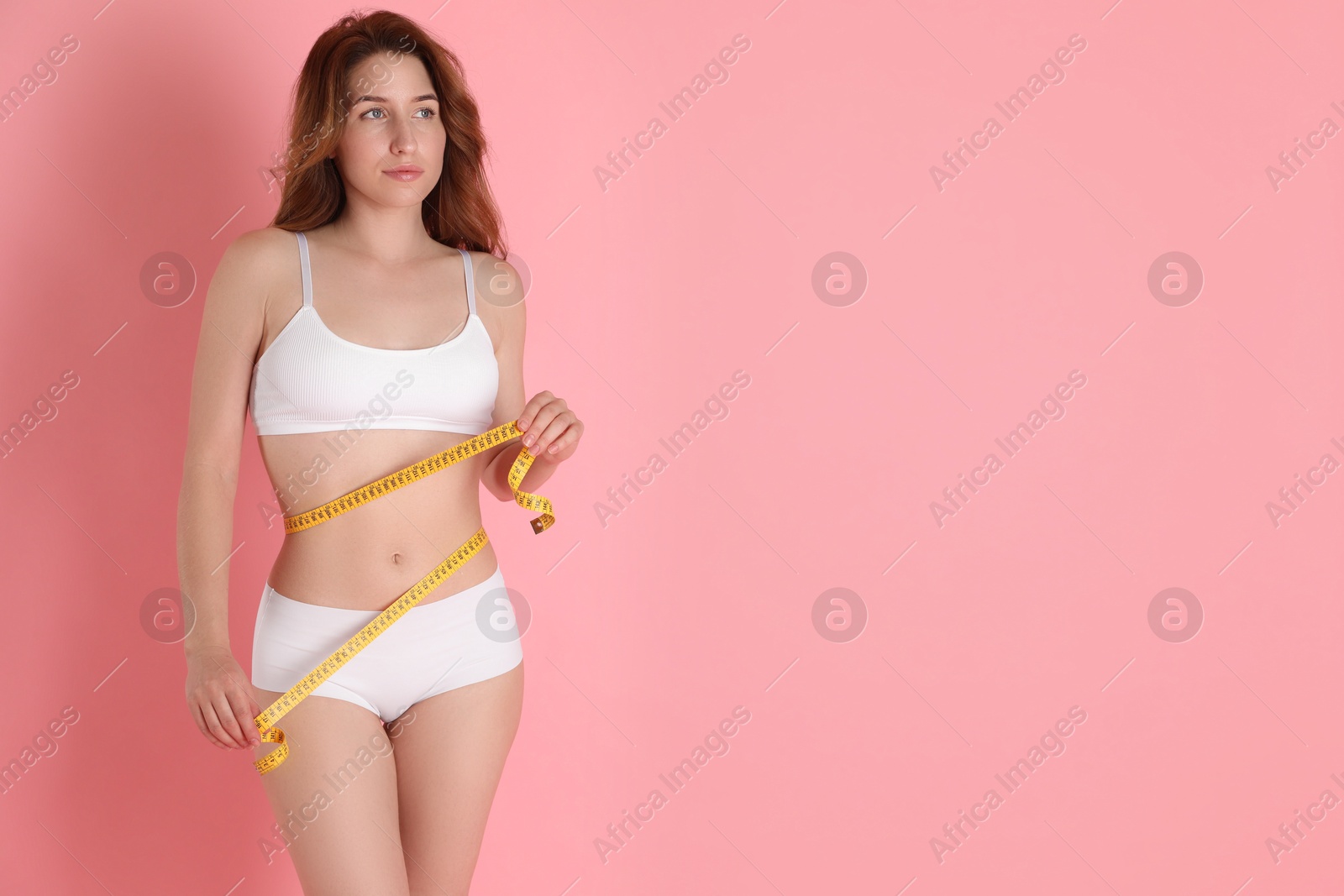 Photo of Woman with measuring tape showing her slim body against pink background, space for text