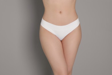 Photo of Woman with slim body posing on grey background, closeup
