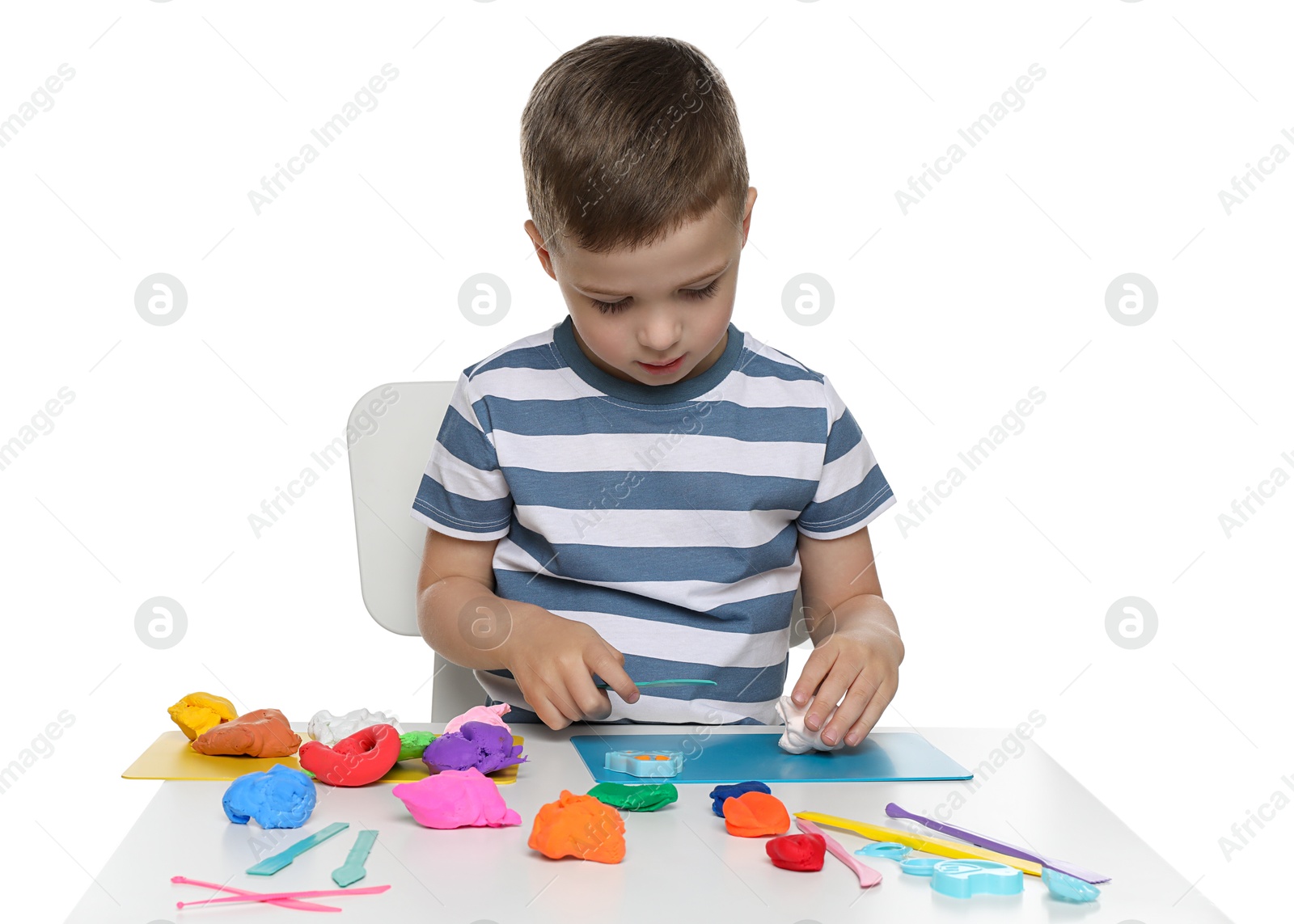 Photo of Little boy sculpting with play dough at table on white background