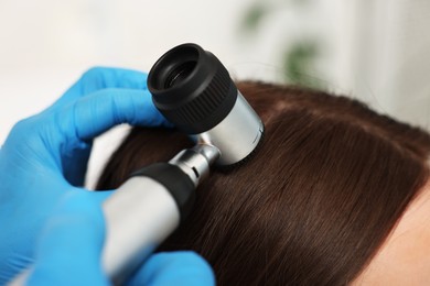 Photo of Trichologist with dermatoscope examining patient`s hair in clinic, closeup