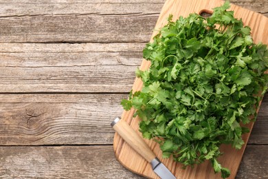 Fresh coriander and knife on wooden table, top view. Space for text