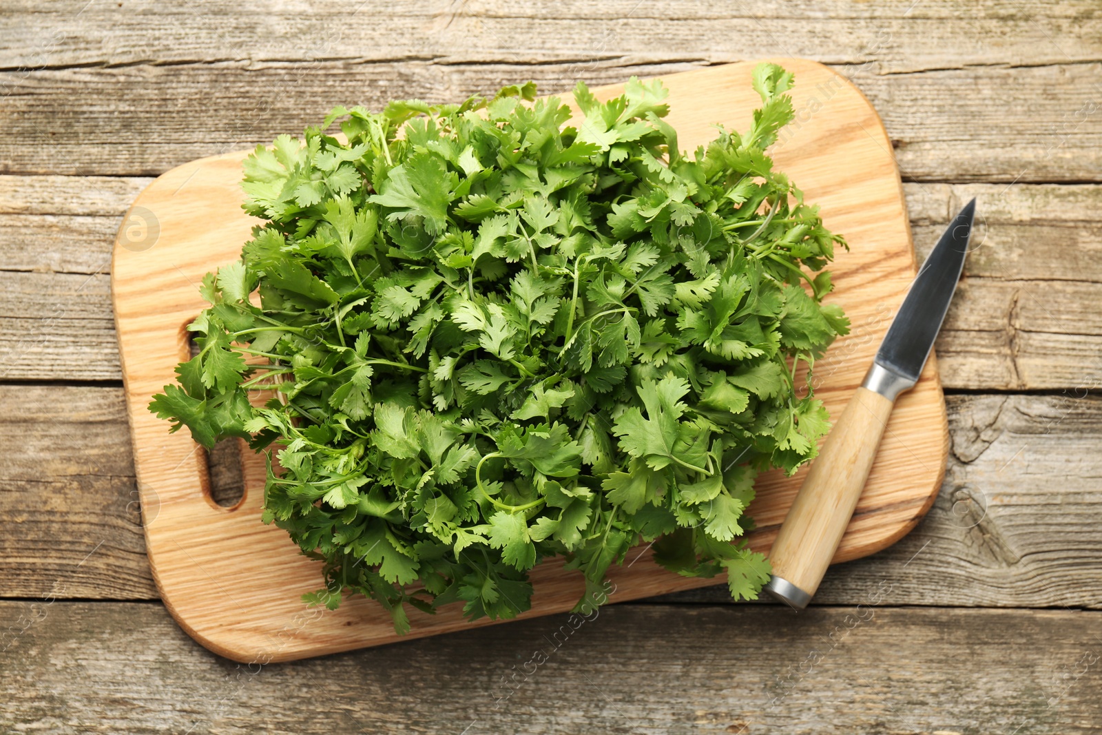 Photo of Fresh coriander and knife on wooden table, top view