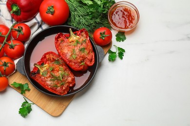 Photo of Tasty stuffed peppers in dish and ingredients on white table, flat lay. Space for text