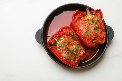 Photo of Tasty stuffed peppers in dish on white table, top view