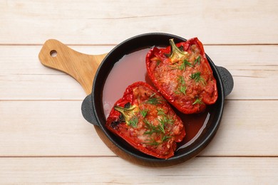 Photo of Tasty stuffed peppers in dish on white wooden table, top view