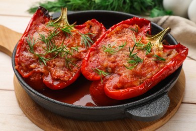 Photo of Tasty stuffed peppers in dish on white wooden table, closeup