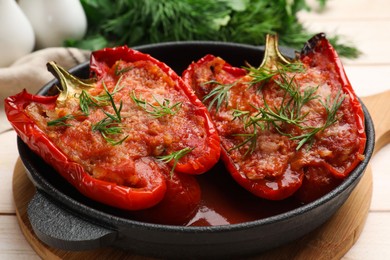 Photo of Tasty stuffed peppers in dish on white wooden table, closeup