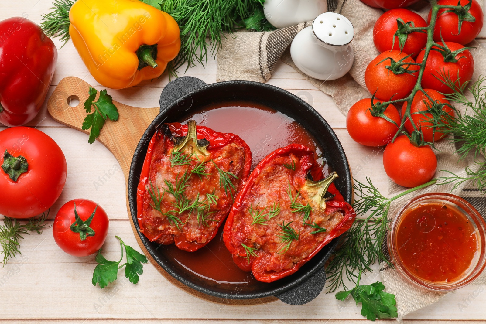 Photo of Tasty stuffed peppers in dish and ingredients on white wooden table, flat lay