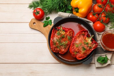 Photo of Tasty stuffed peppers in dish and ingredients on white wooden table, flat lay. Space for text