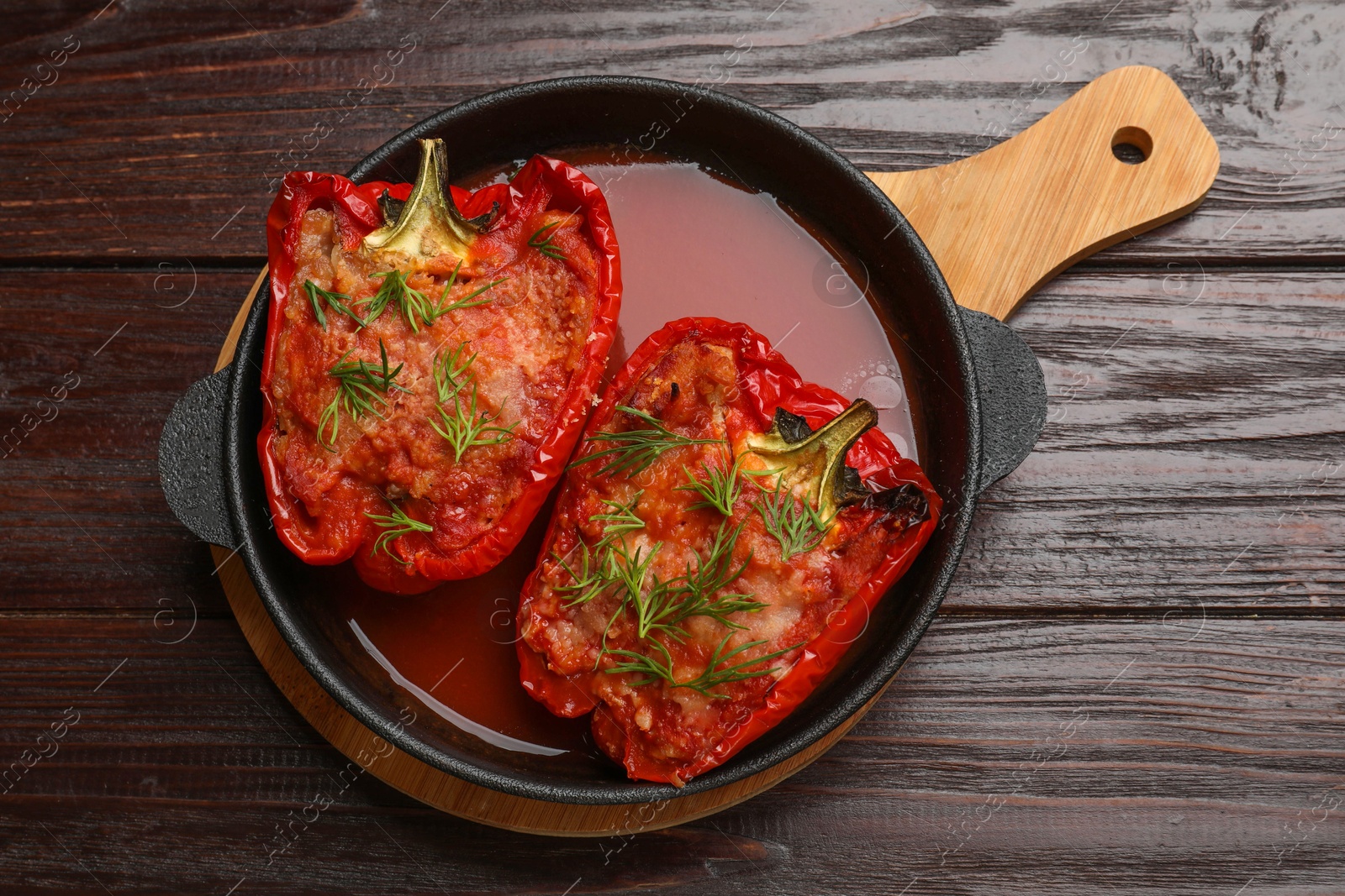 Photo of Tasty stuffed peppers in dish on wooden table, top view