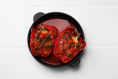 Photo of Tasty stuffed peppers in dish on white tiled table, top view