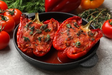 Photo of Tasty stuffed peppers in dish and ingredients on light grey table, closeup