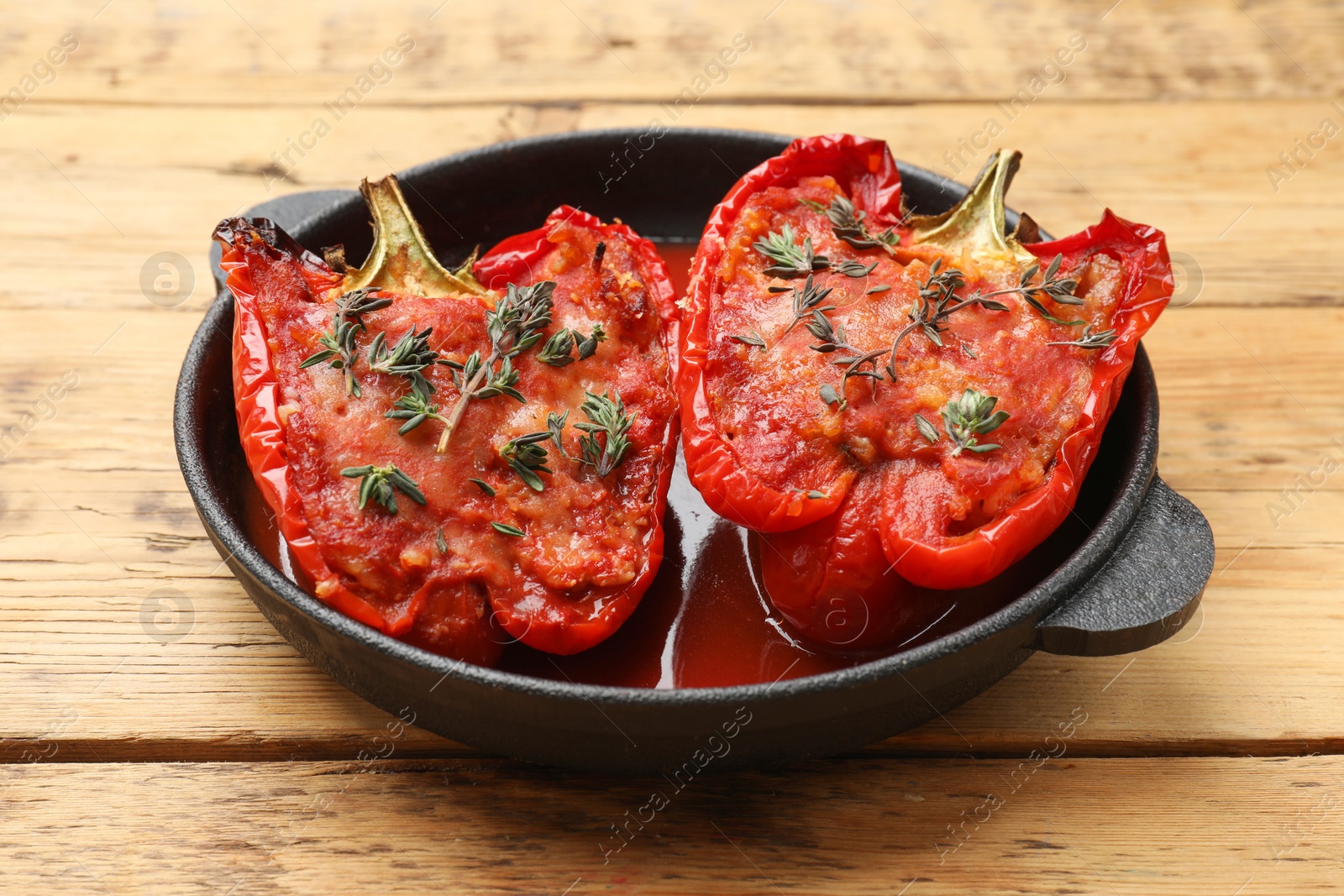 Photo of Tasty stuffed peppers in dish on wooden table