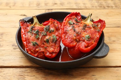 Photo of Tasty stuffed peppers in dish on wooden table