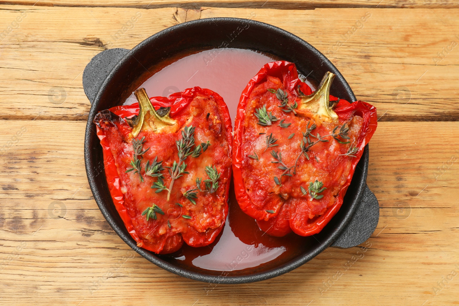 Photo of Tasty stuffed peppers in dish on wooden table, top view