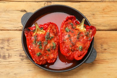 Photo of Tasty stuffed peppers in dish on wooden table, top view