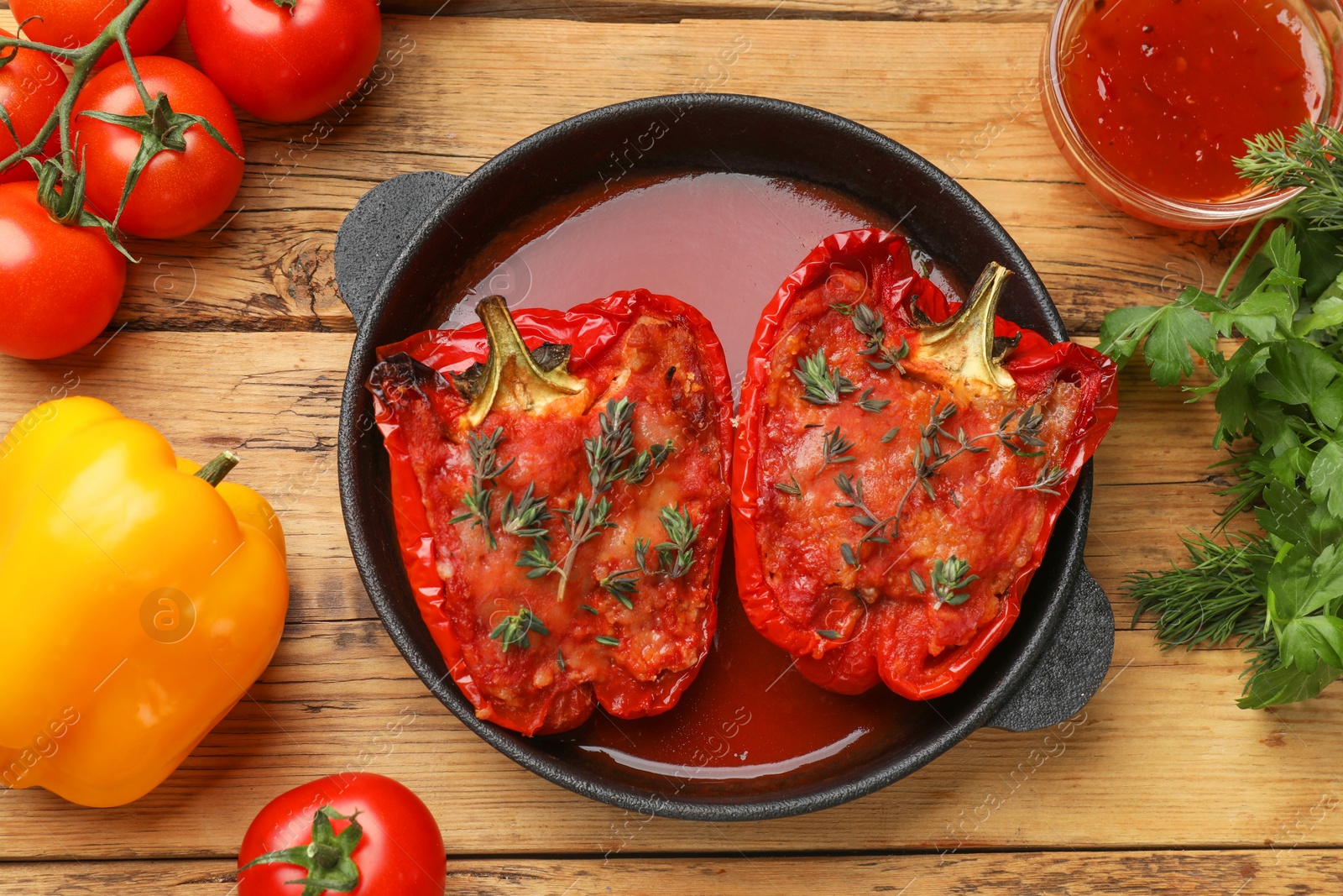 Photo of Tasty stuffed peppers in dish and ingredients on wooden table, flat lay