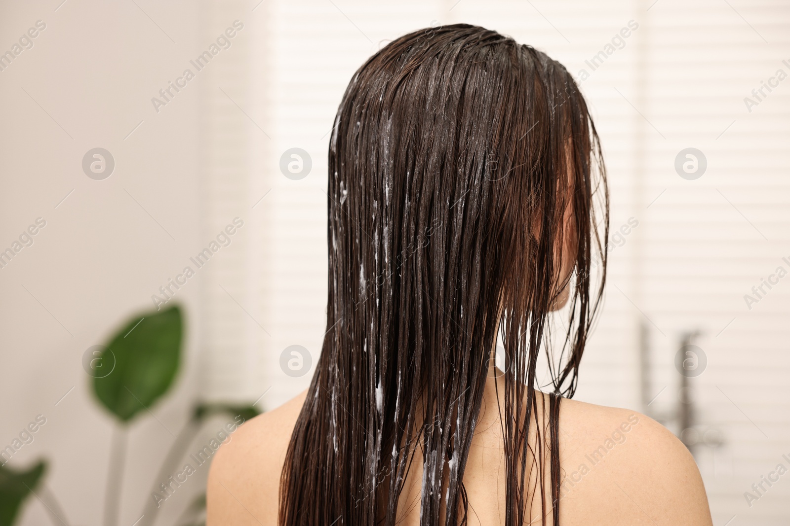 Photo of Woman with cosmetic hair mask in bathroom