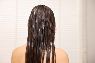 Woman with hair mask in bathroom, back view