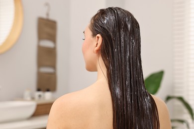 Photo of Woman with cosmetic hair mask in bathroom