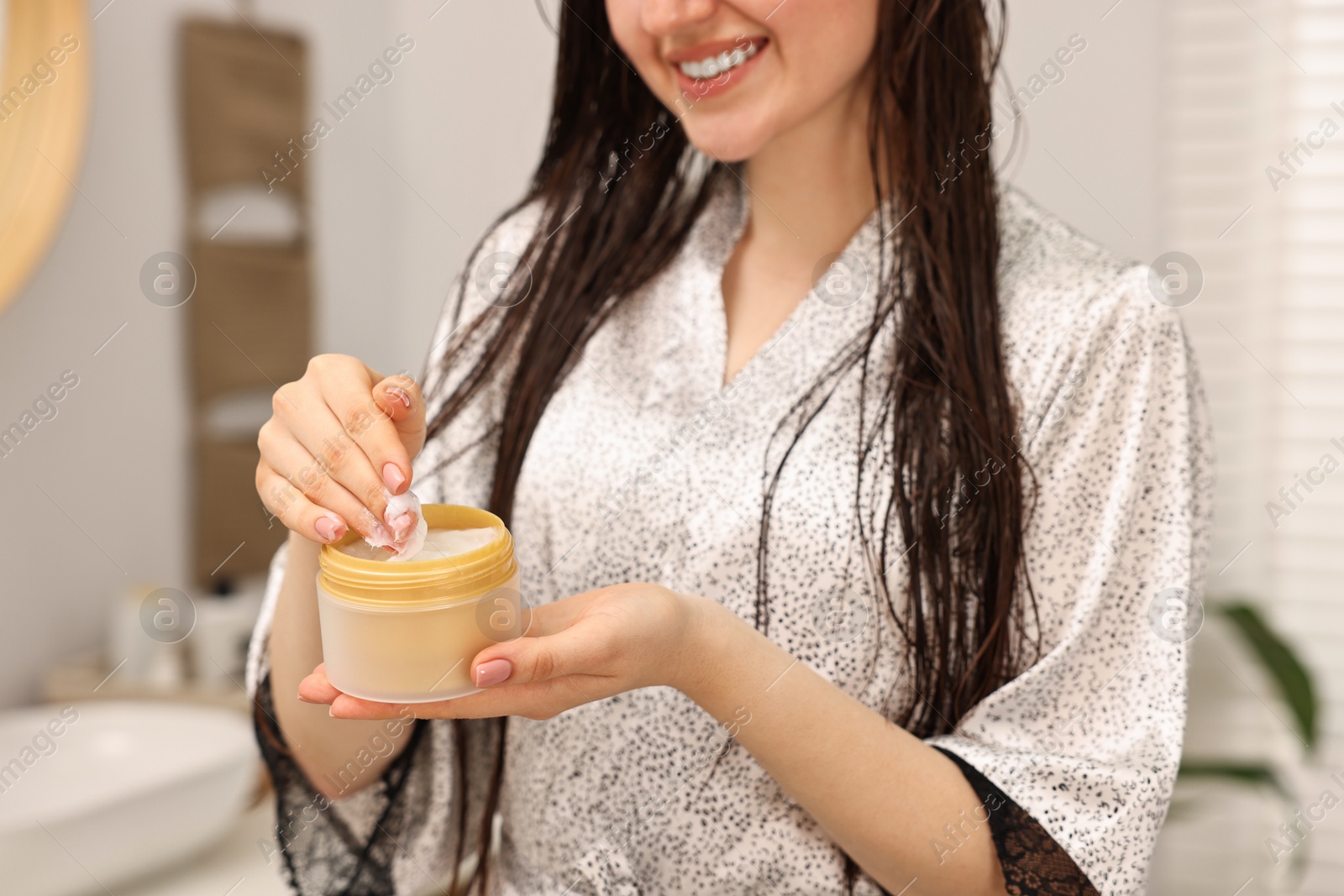 Photo of Woman with jar of hair mask in bathroom, closeup