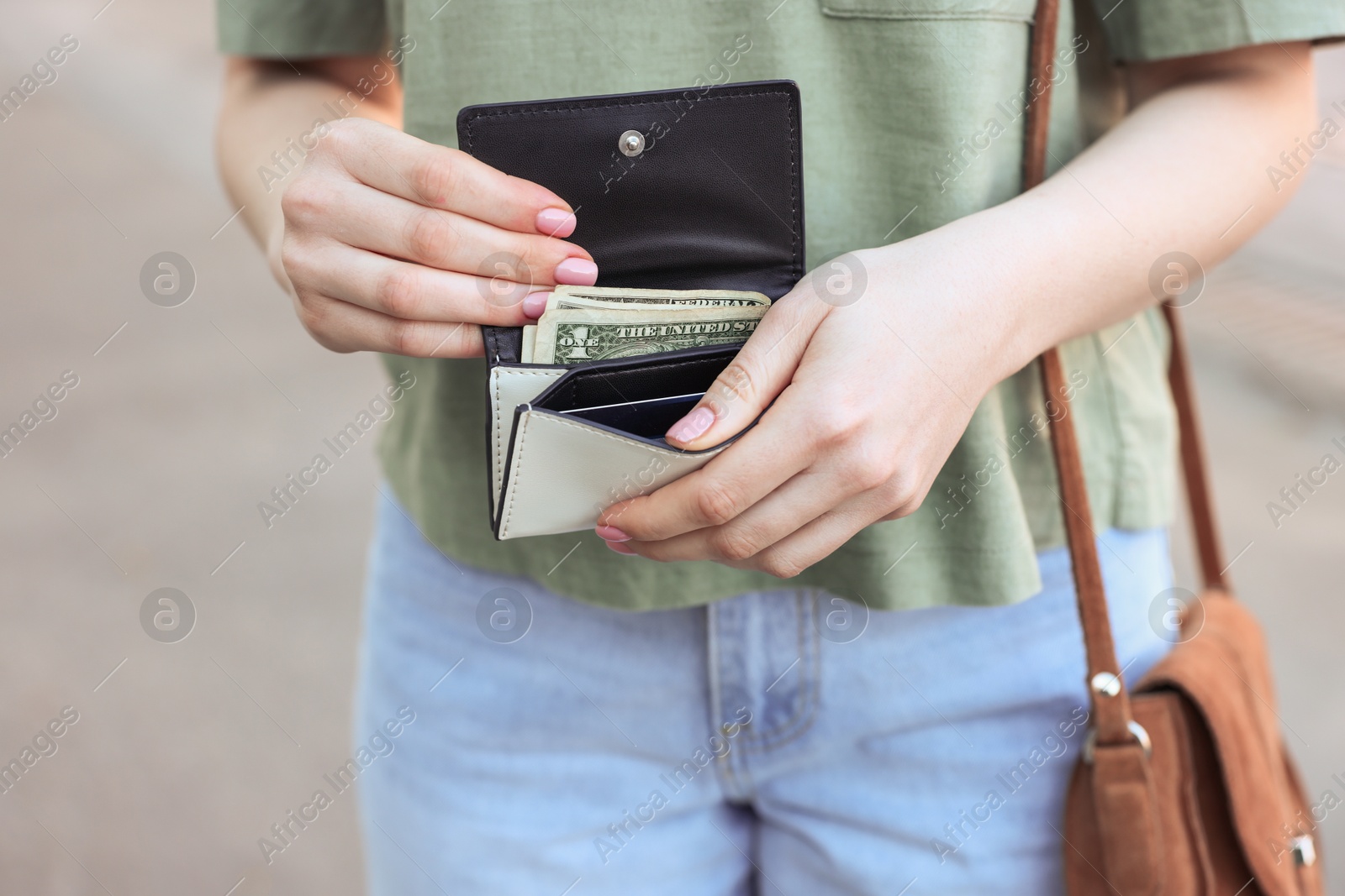 Photo of Woman holding purse with banknotes outdoors, closeup