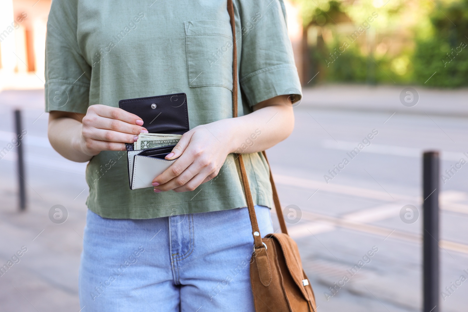 Photo of Woman holding purse with banknotes outdoors, closeup. Space for text