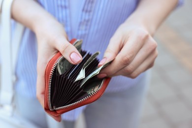 Photo of Woman holding purse with banknotes outdoors, closeup