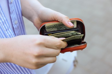 Photo of Woman holding purse with banknotes outdoors, closeup