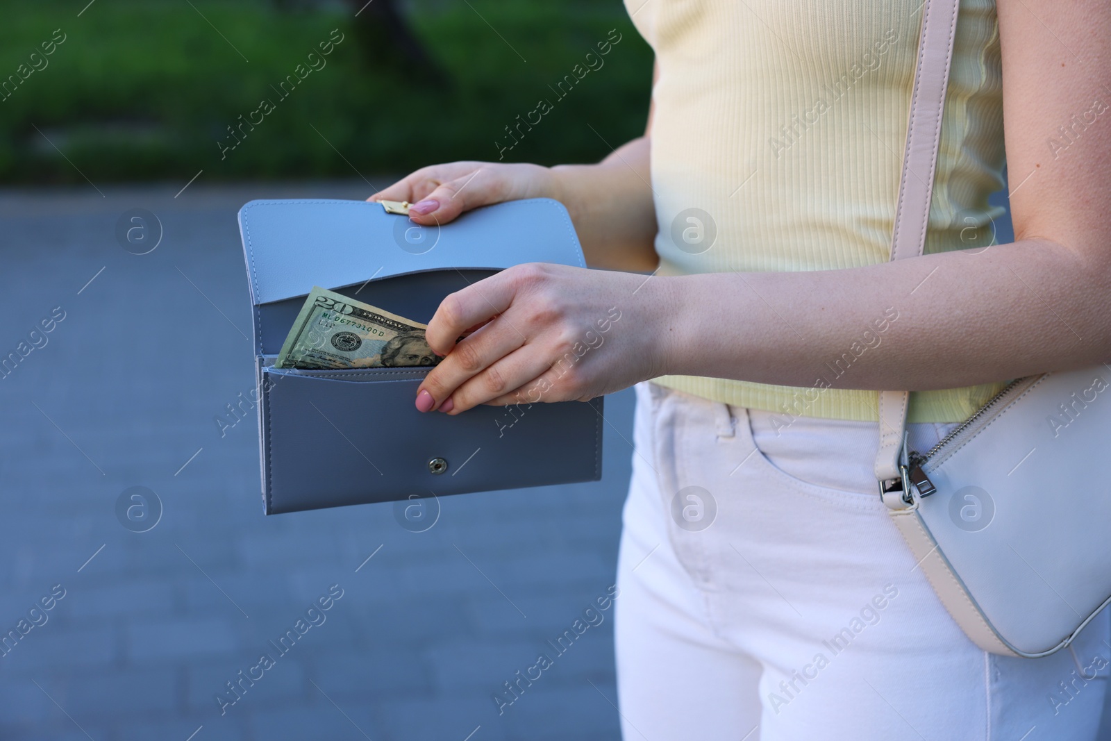 Photo of Woman holding purse with banknotes outdoors, closeup