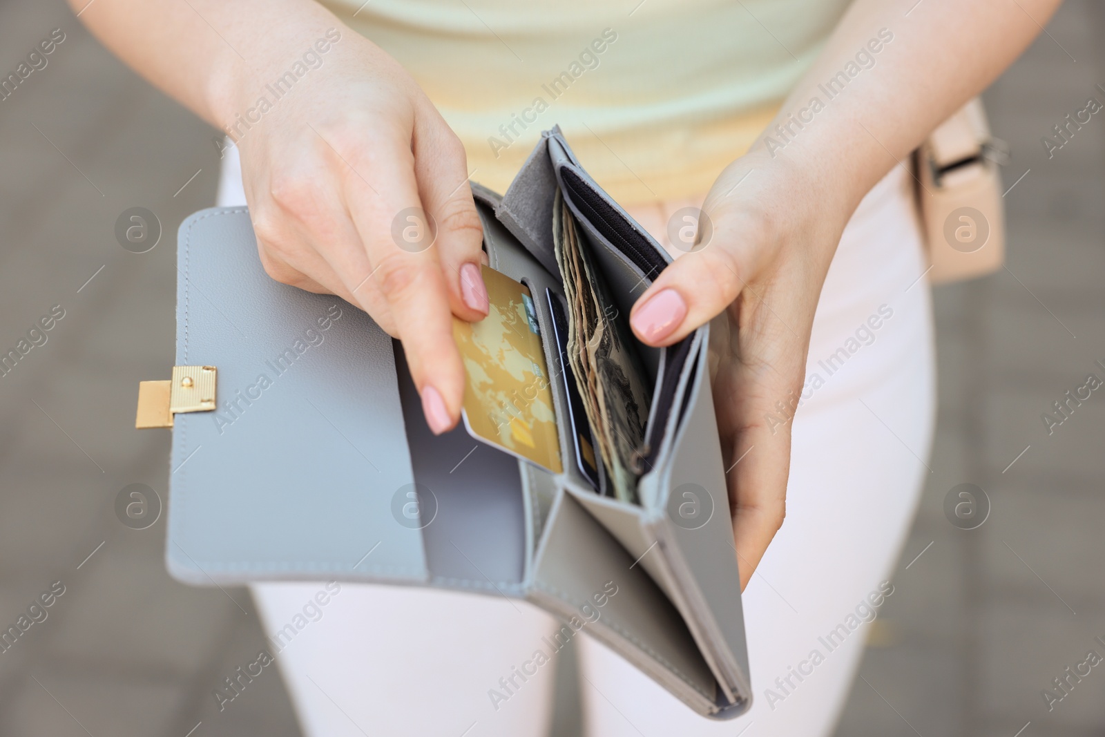 Photo of Woman holding purse with credit card outdoors, closeup