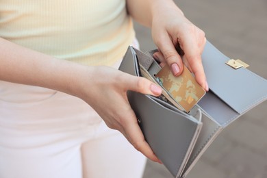 Photo of Woman holding purse with credit card outdoors, closeup