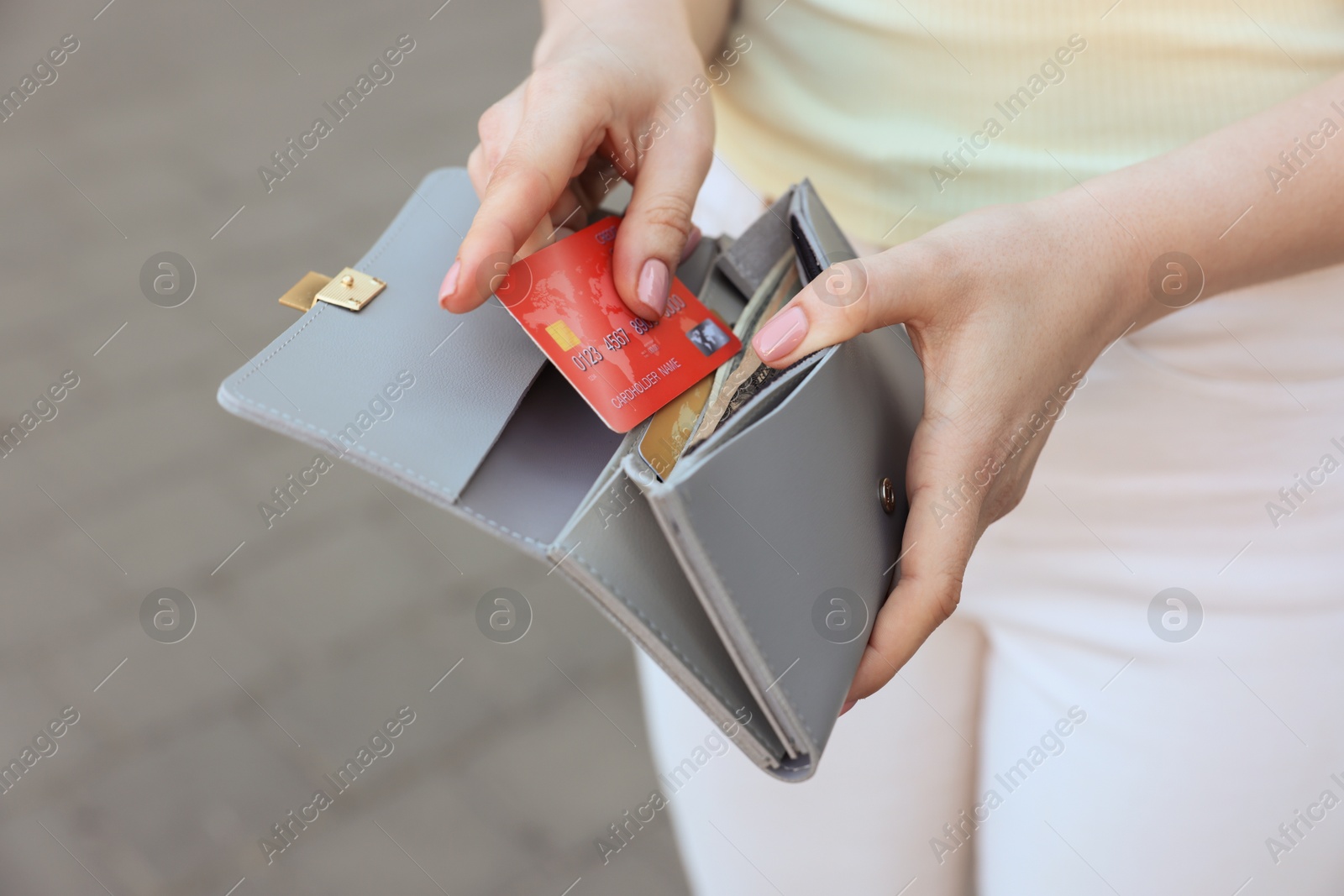 Photo of Woman holding purse with credit card outdoors, closeup