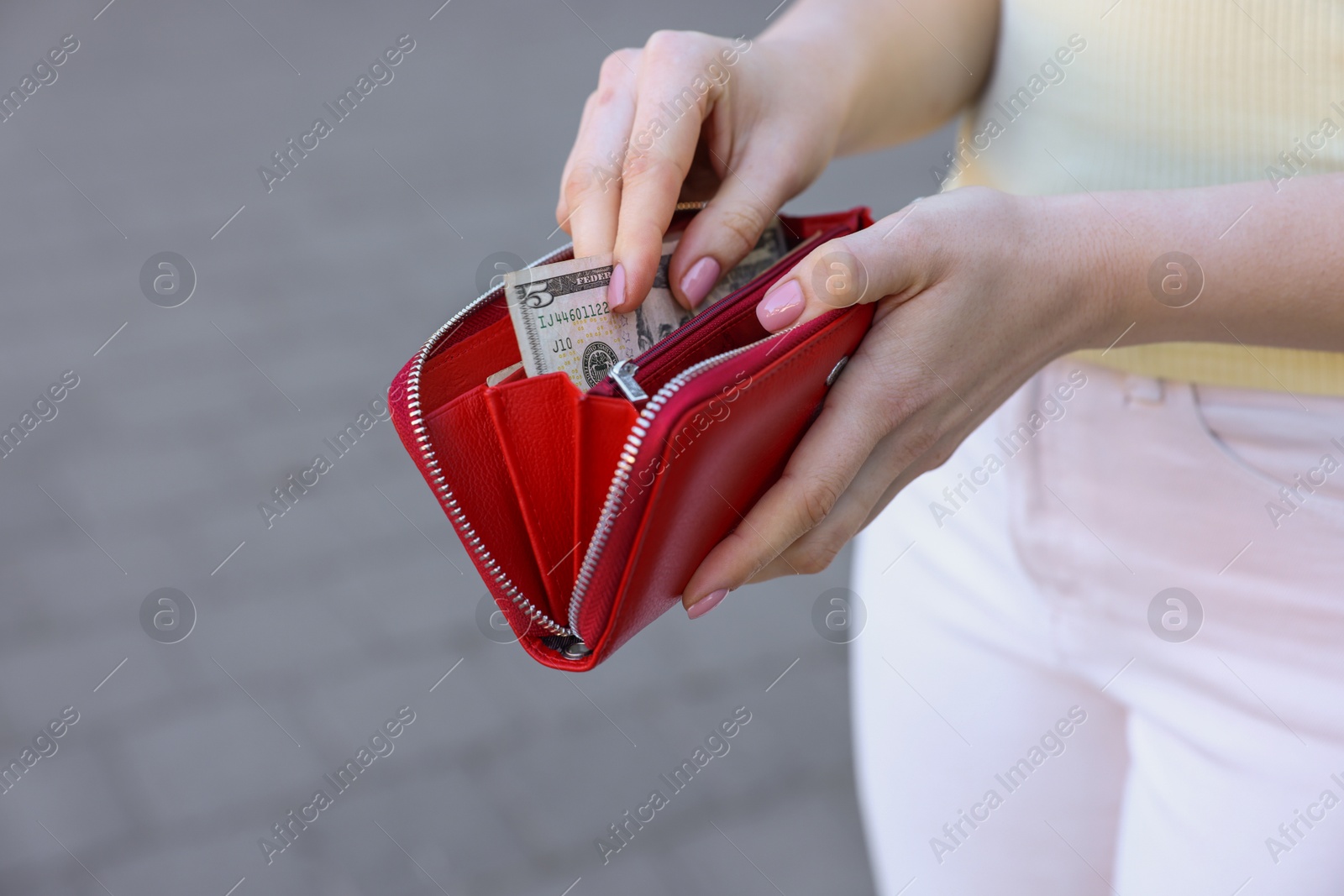 Photo of Woman holding purse with banknotes outdoors, closeup