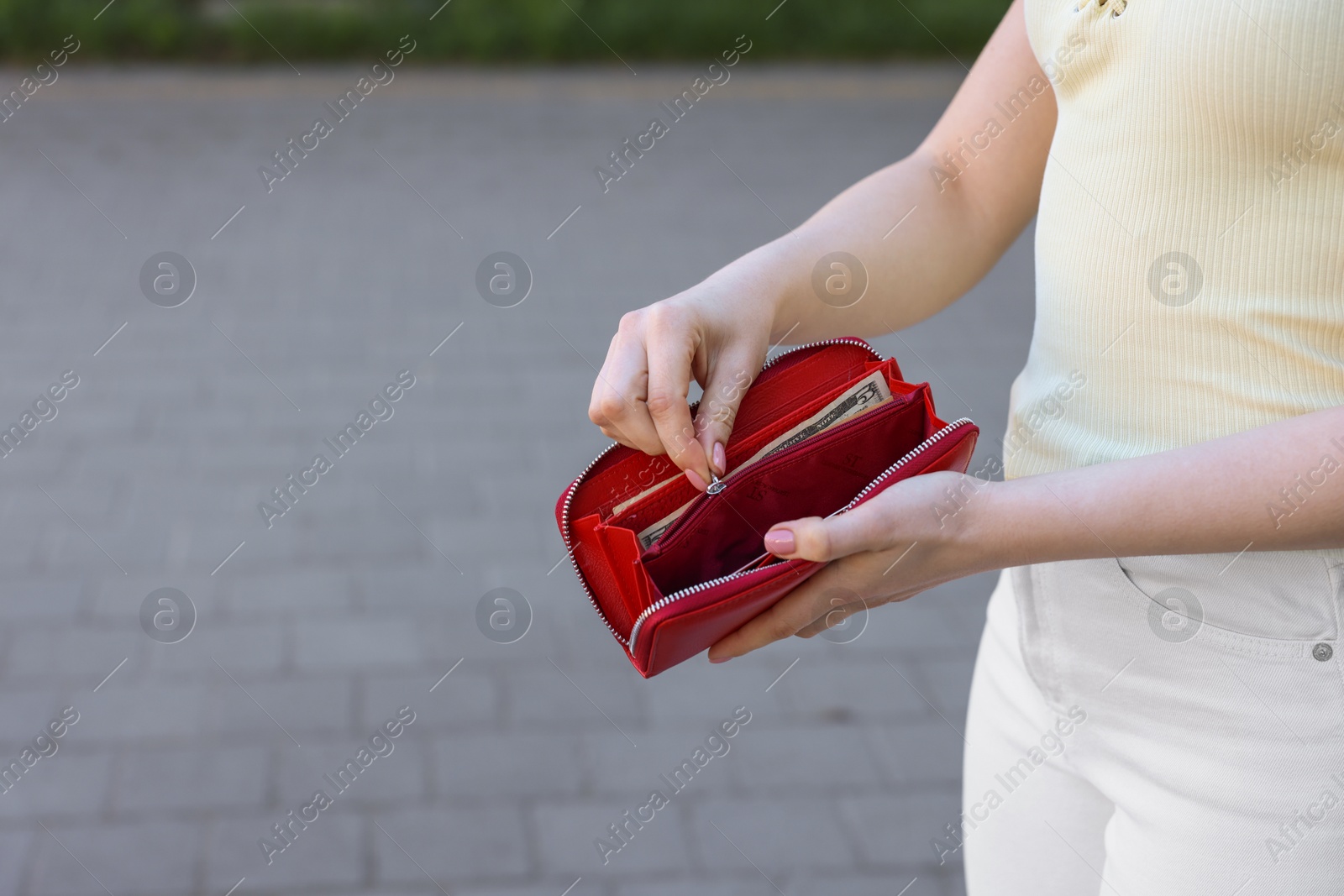 Photo of Woman holding purse with banknotes outdoors, closeup. Space for text