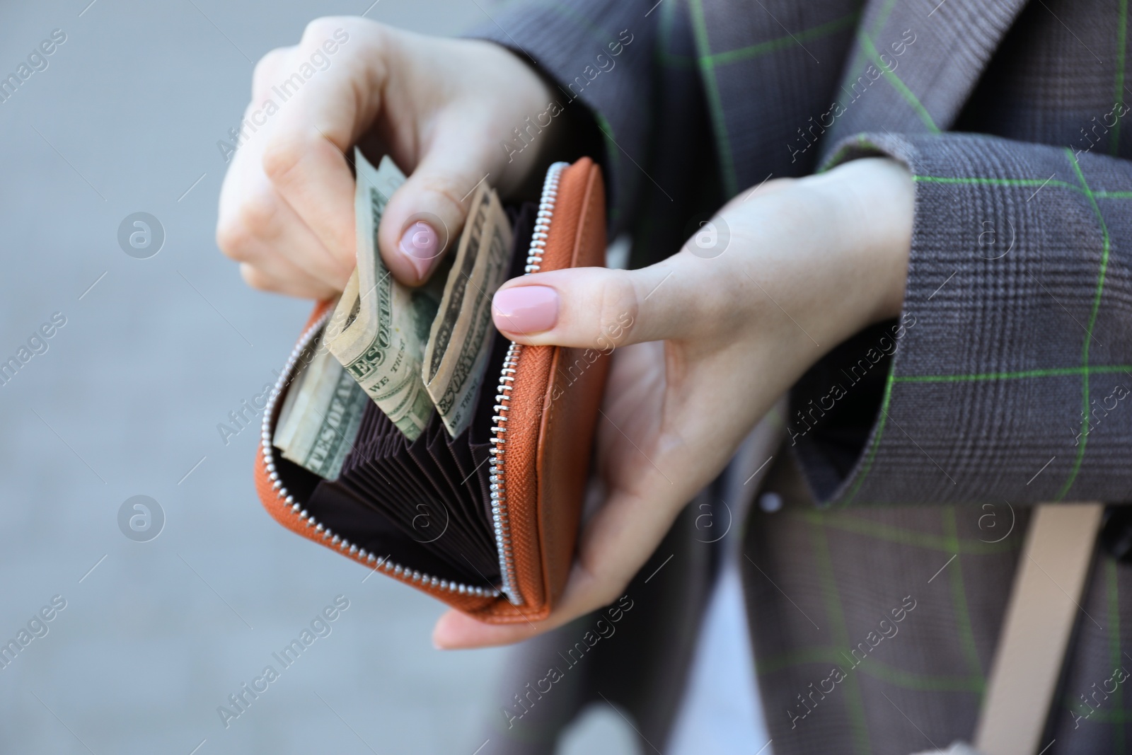 Photo of Woman holding purse with banknotes outdoors, closeup