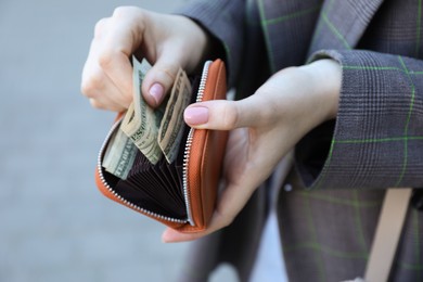 Woman holding purse with banknotes outdoors, closeup