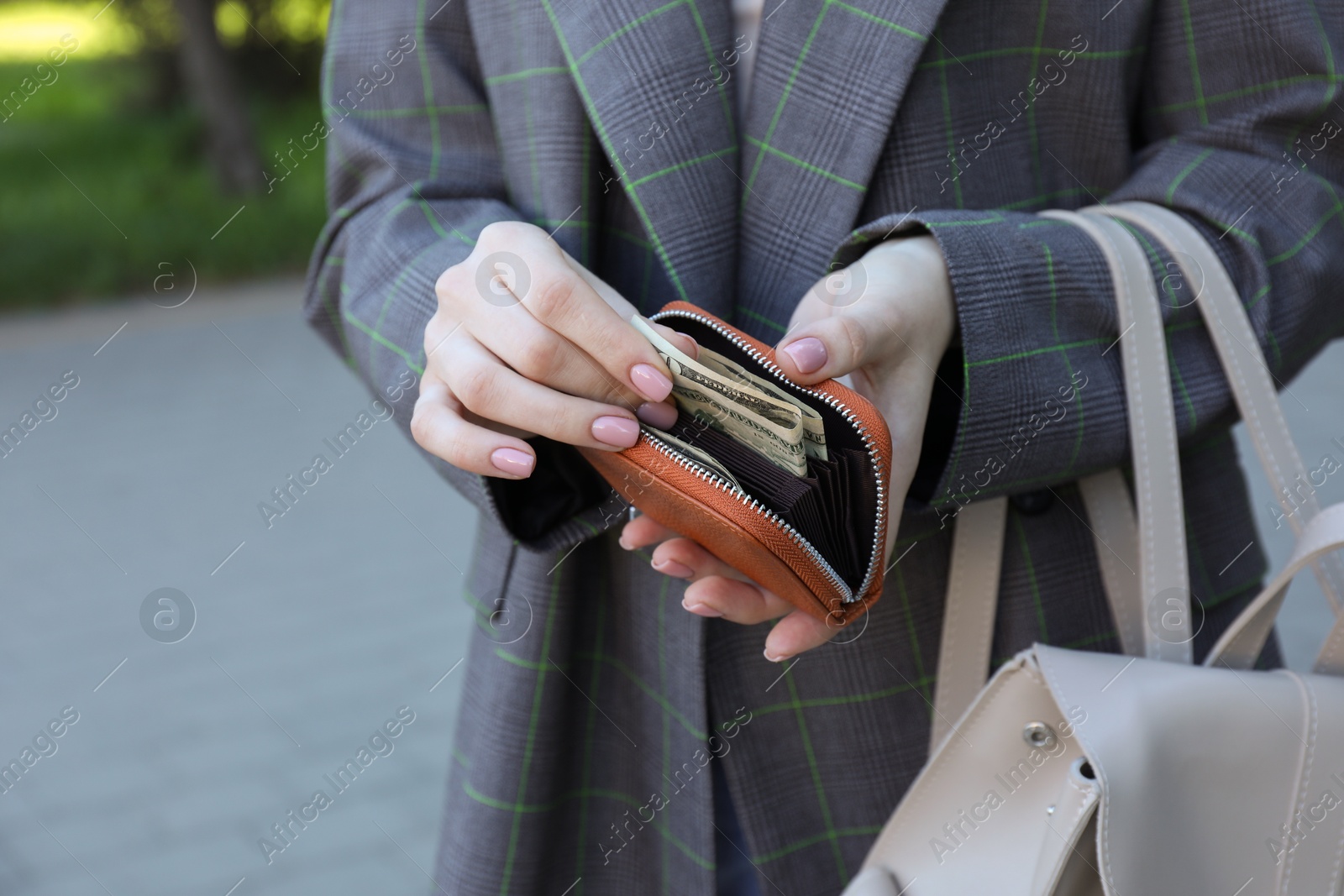 Photo of Woman holding purse with banknotes outdoors, closeup