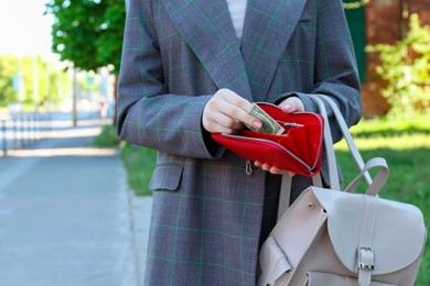 Photo of Woman holding purse with banknotes outdoors, closeup. Space for text