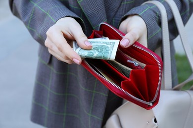 Photo of Woman holding purse with banknotes outdoors, closeup