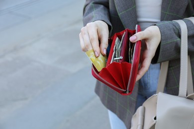 Woman holding purse with banknotes outdoors, closeup. Space for text