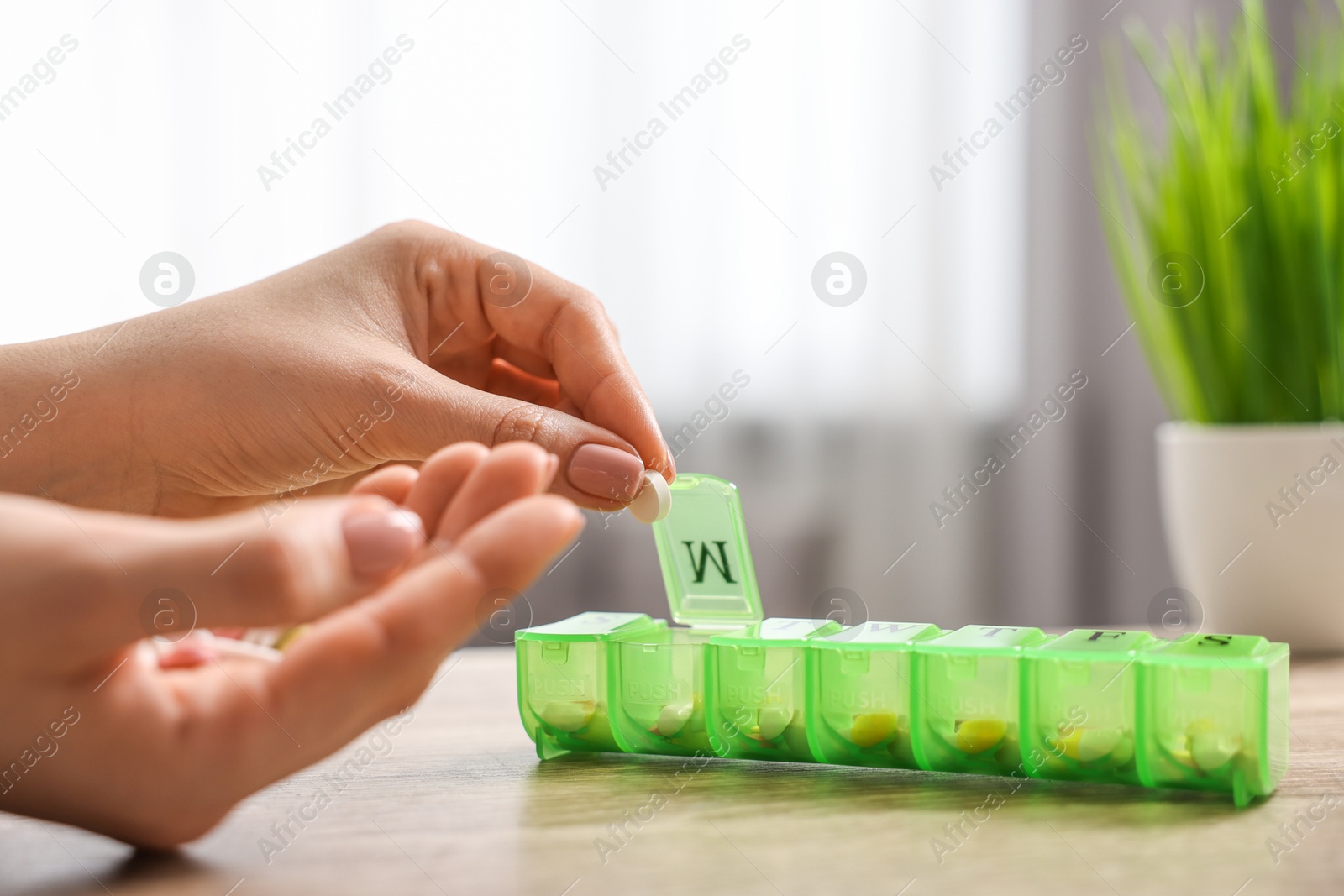 Photo of Woman with pills and organizer at wooden table, closeup