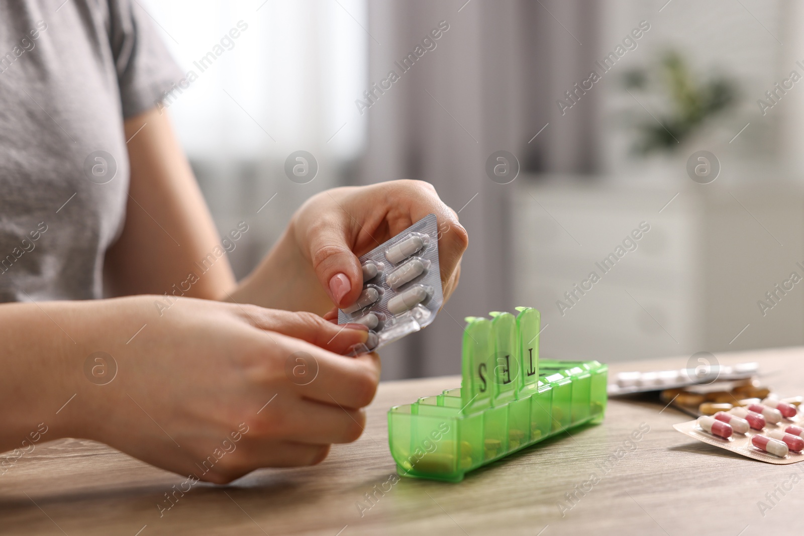 Photo of Woman with pills and organizer at wooden table, closeup