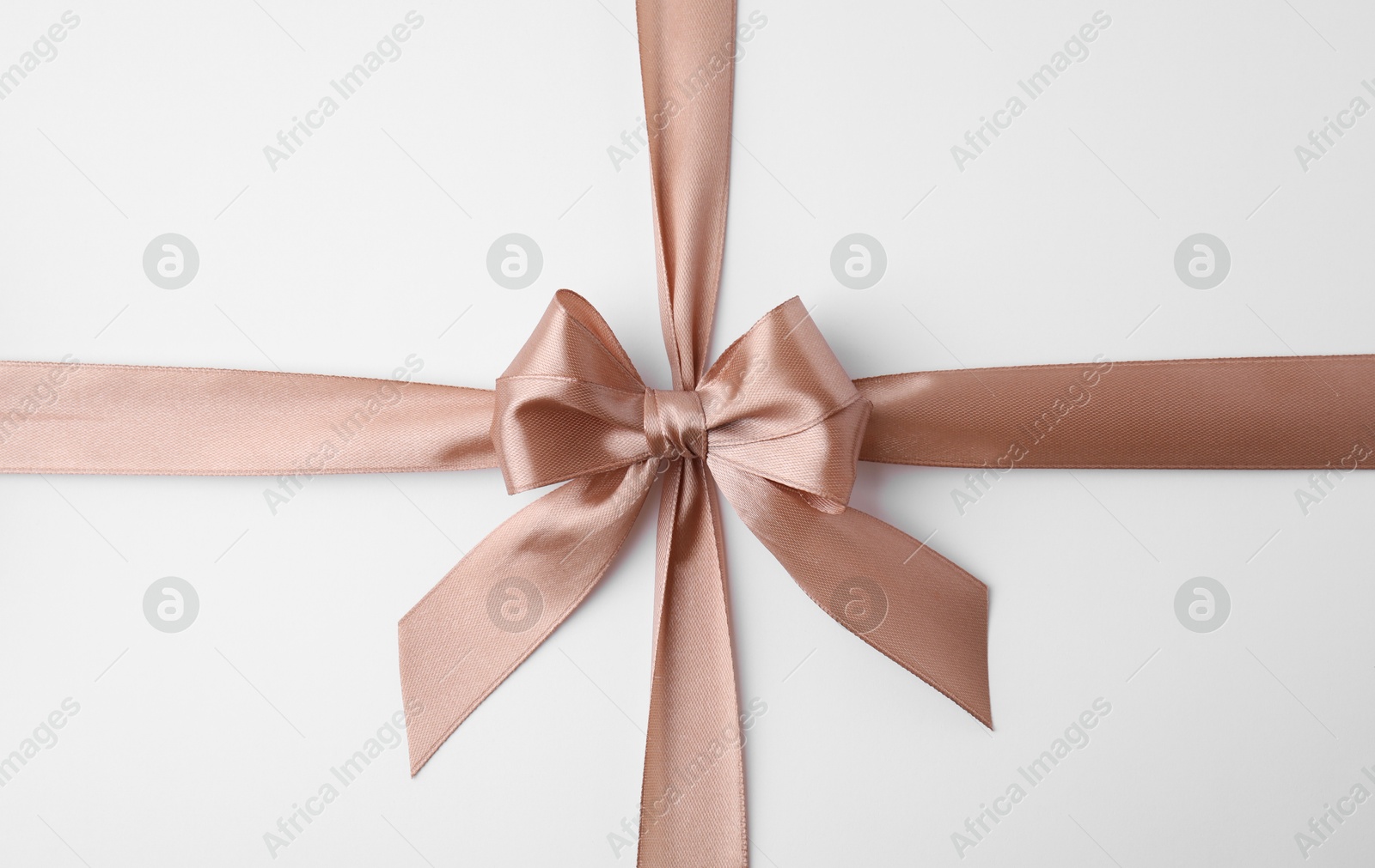 Photo of Beige satin ribbon with bow on white background, top view